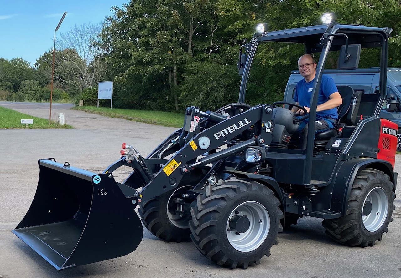 Eight shirts arranged on table in black, olive, grey, blue, white, red, mustard, and green.